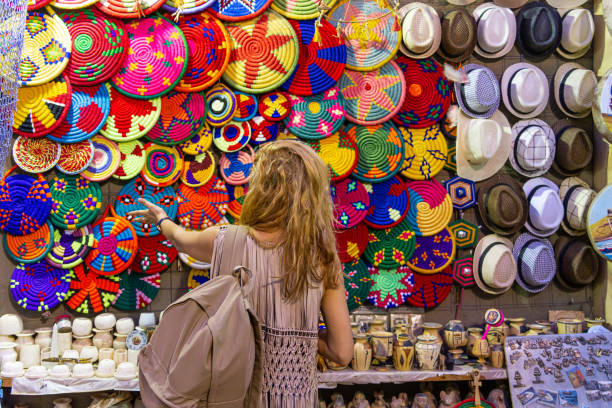 Women standing in front of colorful woven baskets and bags on  a market stall in the souk in Aswan, Egypt